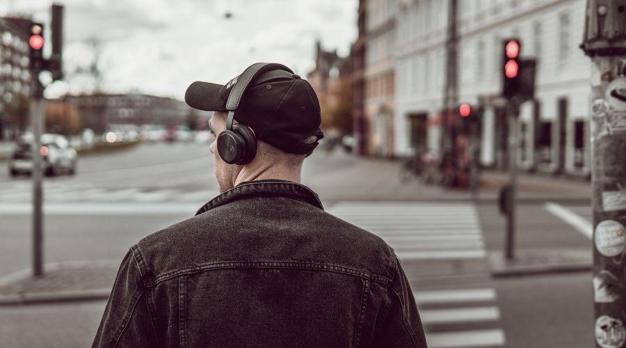 Listening. City background. Headphones on.