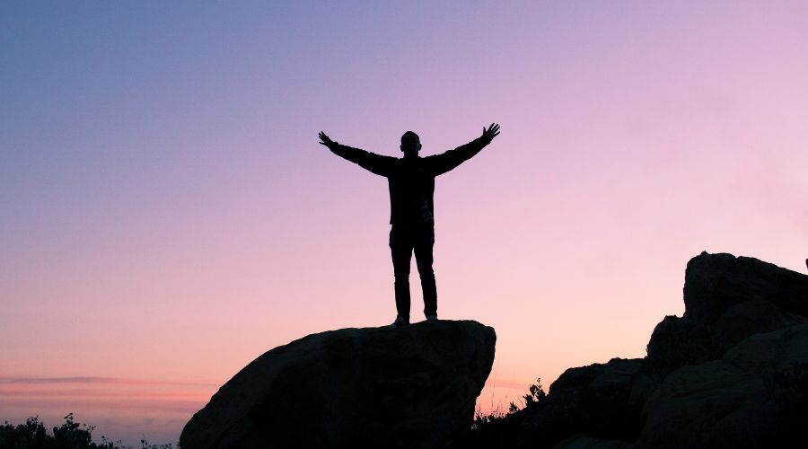 Confidence vs Resolve: A person standing on top of a mountain